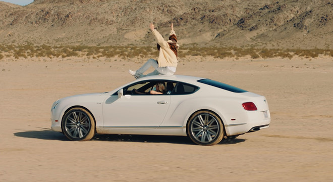 Sơn Tùng MT-P ngồi trên nóc chiếc xe Bentley Continental GT Speed trong MV mới vừa ra mắt.