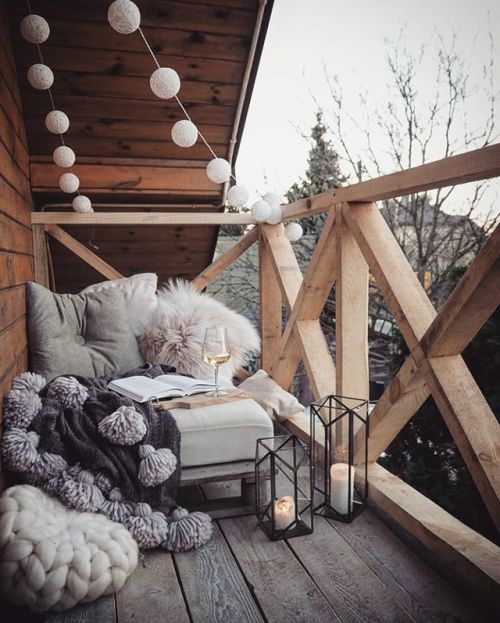 Đèn nến, dây đèn trang trí, chỗ ngồi ấm áp với ghế ngồi ấm áp cùng chiếc chăn mềm mại cho không gian ban công hiện đại. trang trí ban công