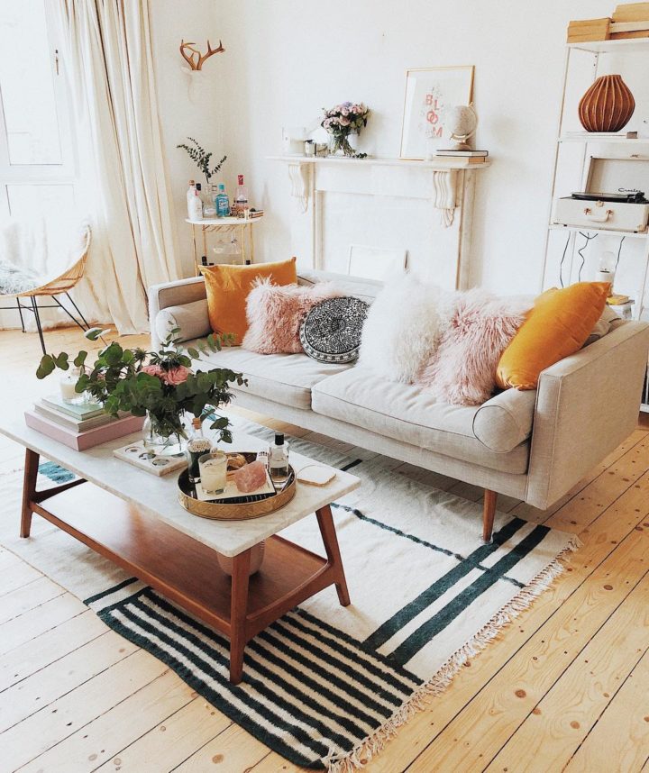 H&igrave;nh ảnh ph&ograve;ng kh&aacute;ch ngọt ng&agrave;o với sofa trắng sữa, gối tựa l&ocirc;ng h&ocirc;ng phấn, cam, thảm trải kẻ sọc sinh động