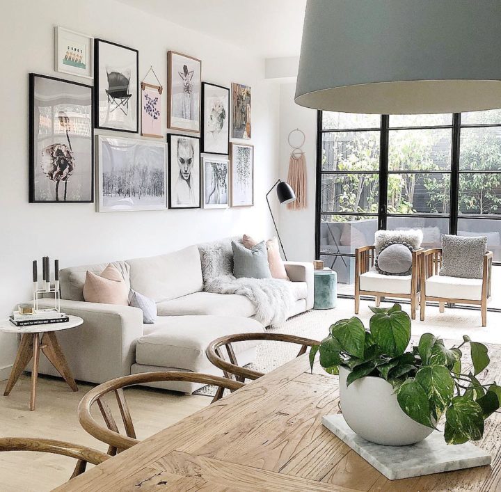 H&igrave;nh ảnh ph&ograve;ng kh&aacute;ch hiện đại, tho&aacute;ng s&aacute;ng với sofa trắng, cửa k&iacute;nh khung đen, tranh treo tường ấn tượng