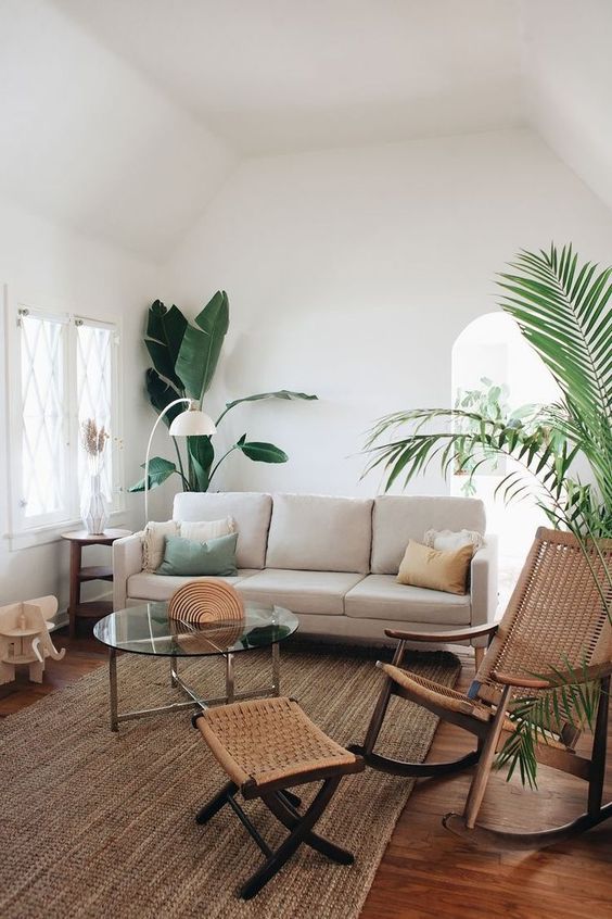 H&igrave;nh ảnh ph&ograve;ng kh&aacute;ch t&ocirc;ng m&agrave;u trắng chủ đạo, ghế sofa &ecirc;m &aacute;i, thảm trải dệt c&oacute;i, c&acirc;y xanh lớn ở g&oacute;c ph&ograve;ng
