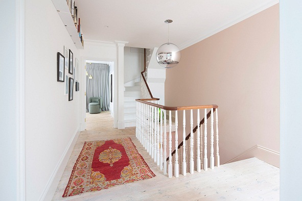 H&igrave;nh ảnh cận cảnh cầu thang được trang tr&iacute; với thảm trải thổ cẩm, tranh treo tường, kệ mở