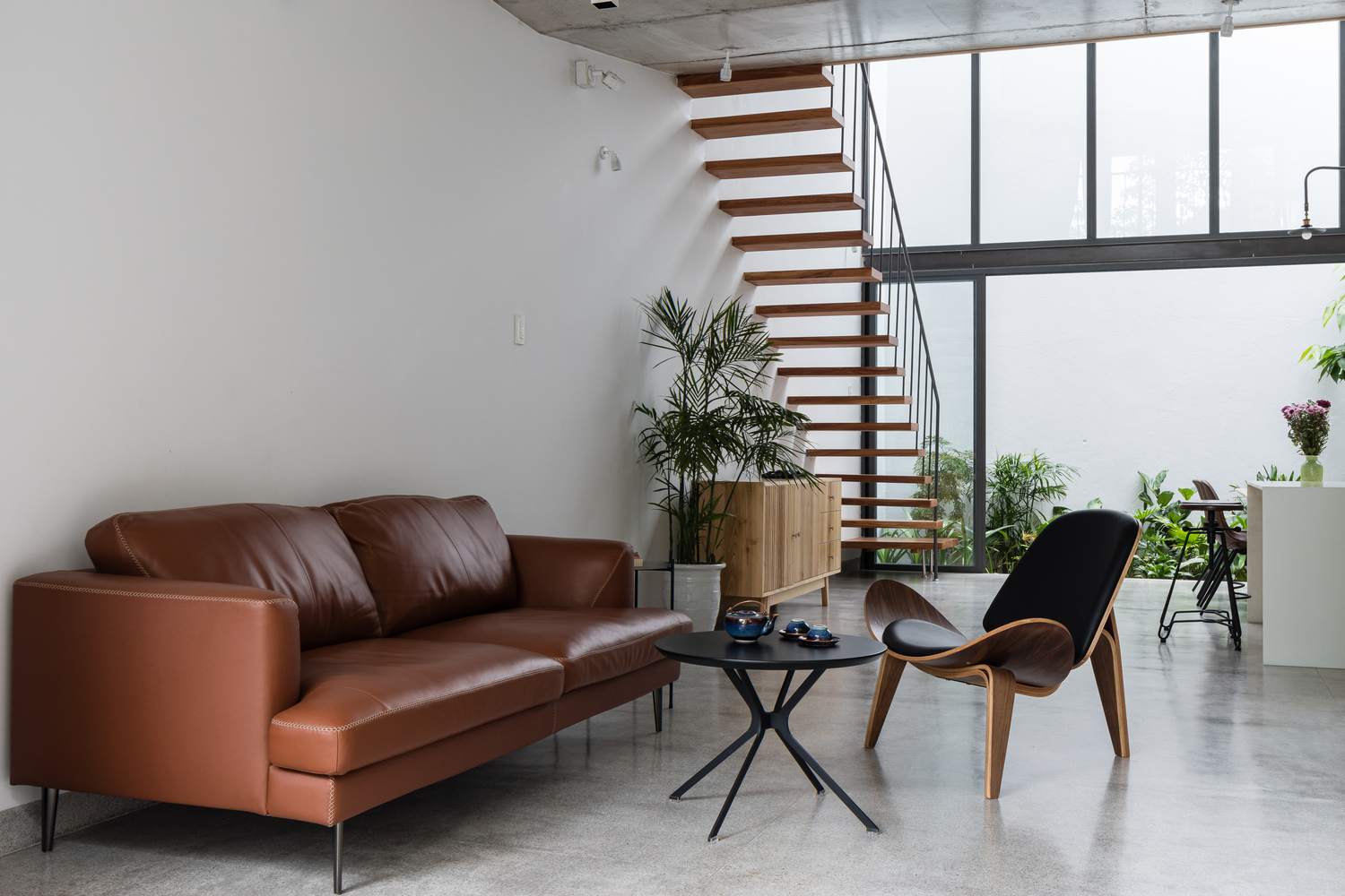 H&igrave;nh ảnh to&agrave;n cảnh ph&ograve;ng kh&aacute;ch với ghế sofa m&agrave;u v&agrave;ng da b&ograve;, b&agrave;n tr&agrave; nhỏ xinh, liền kề đ&oacute; l&agrave; ph&ograve;ng bếp ăn hiện đại