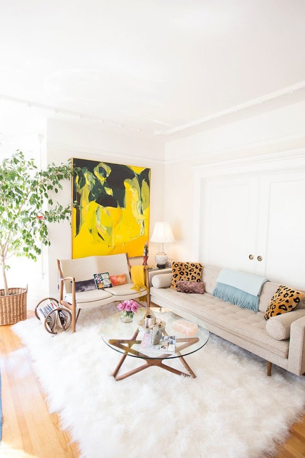 H&igrave;nh ảnh ph&ograve;ng kh&aacute;ch nhỏ ấn tượng với sofa trắng sữa, b&agrave;n tr&agrave; k&iacute;nh, tranh treo tường m&agrave;u v&agrave;ng cam nổi bật