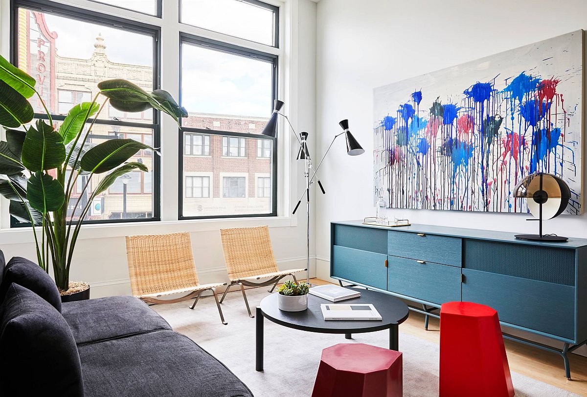 H&igrave;nh ảnh to&agrave;n cảnh ph&ograve;ng kh&aacute;ch nhỏ m&agrave;u trắng chủ đạo với sofa x&aacute;m đen, tủ kệ m&agrave;u xanh dương, tranh treo tường ấn tượng