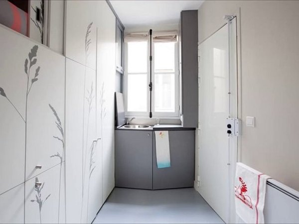 Hình ảnh khu bếp nấu và bồn rửa màu xám đặt cạnh khung cửa sổ kính thoáng sáng
