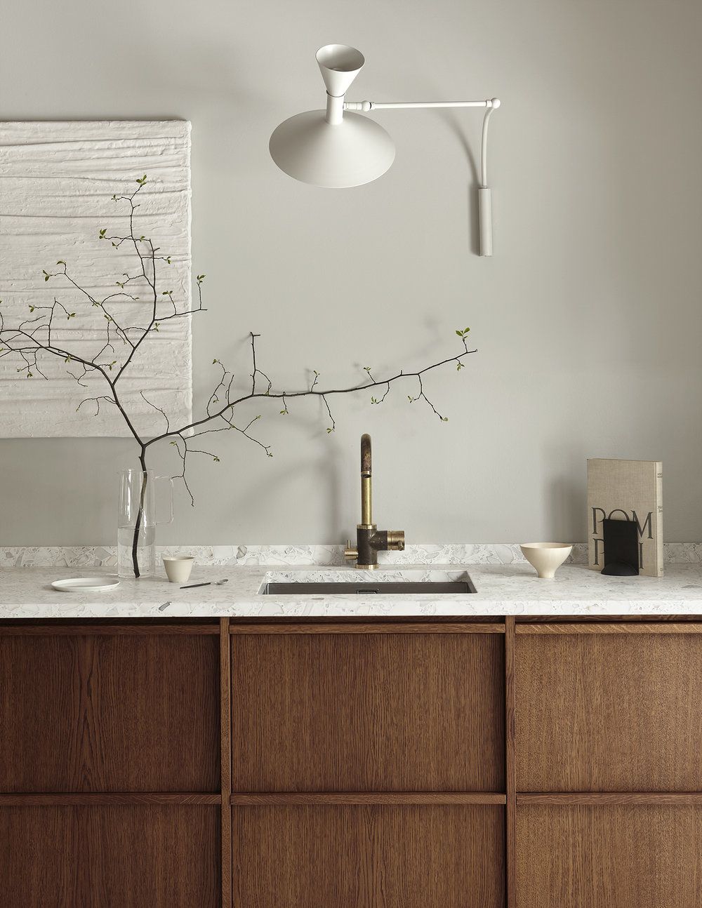 H&igrave;nh ảnh một g&oacute;c ph&ograve;ng bếp với bồn rửa b&aacute;t, bề mặt ốp đ&aacute; m&agrave;u rắng, b&igrave;nh c&acirc;y trang tr&iacute;