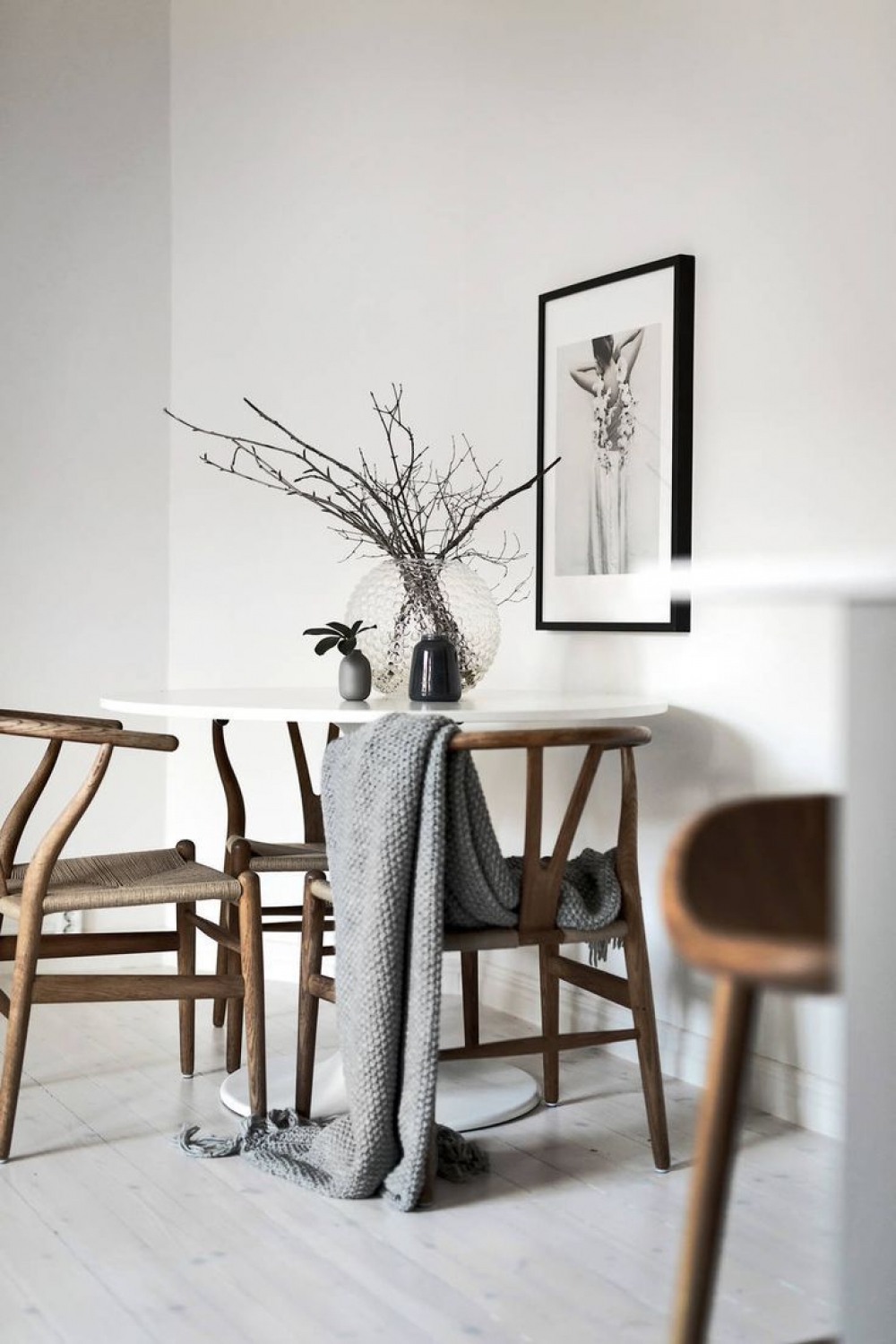 H&igrave;nh ảnh cận cảnh g&oacute;c ăn uống phong c&aacute;ch Japandi với b&agrave;n tr&ograve;n nhỏ xinh, ph&iacute;a tr&ecirc;n đặt b&igrave;nh c&acirc;y trang tr&iacute; tinh tế, xung quanh đặt ghế tựa gỗ mộc mạc.