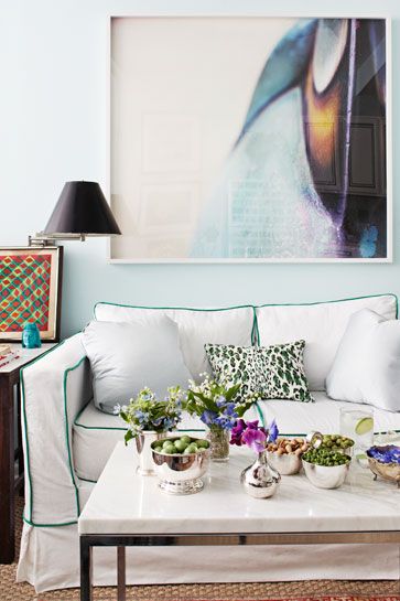 Hình ảnh một góc phòng khách nhỏ với sofa màu trắng, đèn xoay để bàn cạnh sofa, bàn trà mặt đá cẩm thạch 