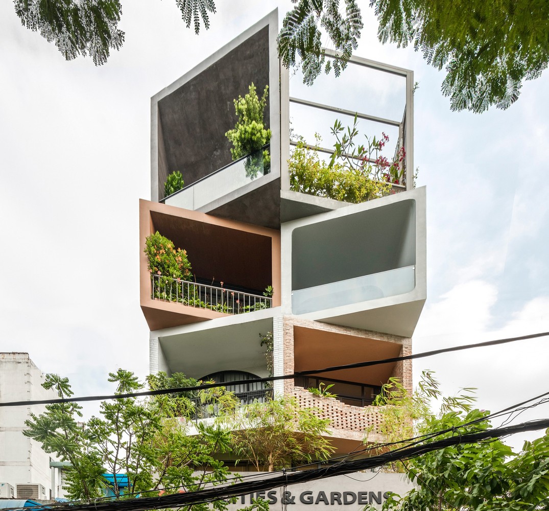 Hình ảnh cận cảnh mặt tiền nhà phố 7 tầng ở TP.HCM với các khối hộp bằng gạch và bê tông ấn tượng, ban công trồng cây xanh
