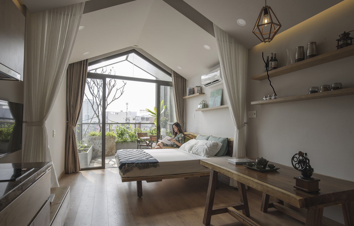 Căn hộ rừng trên tầng 6 nhà phố Sài Gòn Hình ảnh phòng ngủ rộng thoáng trên tầng 6 nhà phố với rèm sát trần, cửa lớn mở ra khu vườn ban công xanh tốt
