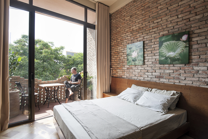 Phòng ngủ trong nhà phố có thiết kế ấn tượng Hình ảnh phòng ngủ trong nhà phố với tường gạch nung đỏ, cửa kính lớn mở ra ban công thoáng đãng