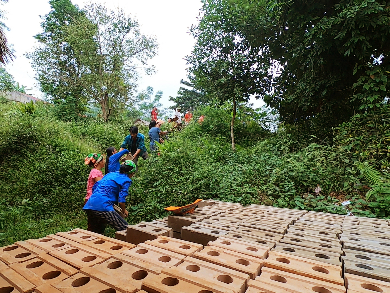 Hình ảnh người dân địa phương tập kết gạch không nung xây dựng trường tiểu học.