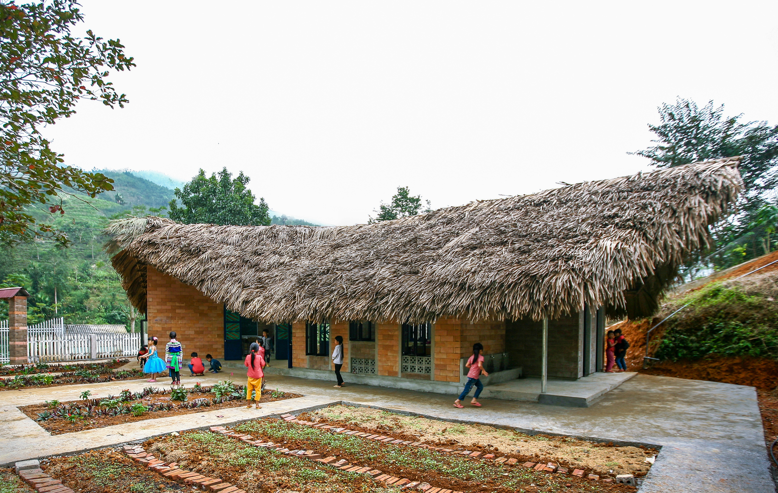 Hình ảnh các em học sinh đang vui đùa nơi sân trường tiểu học có mái lợp tranh