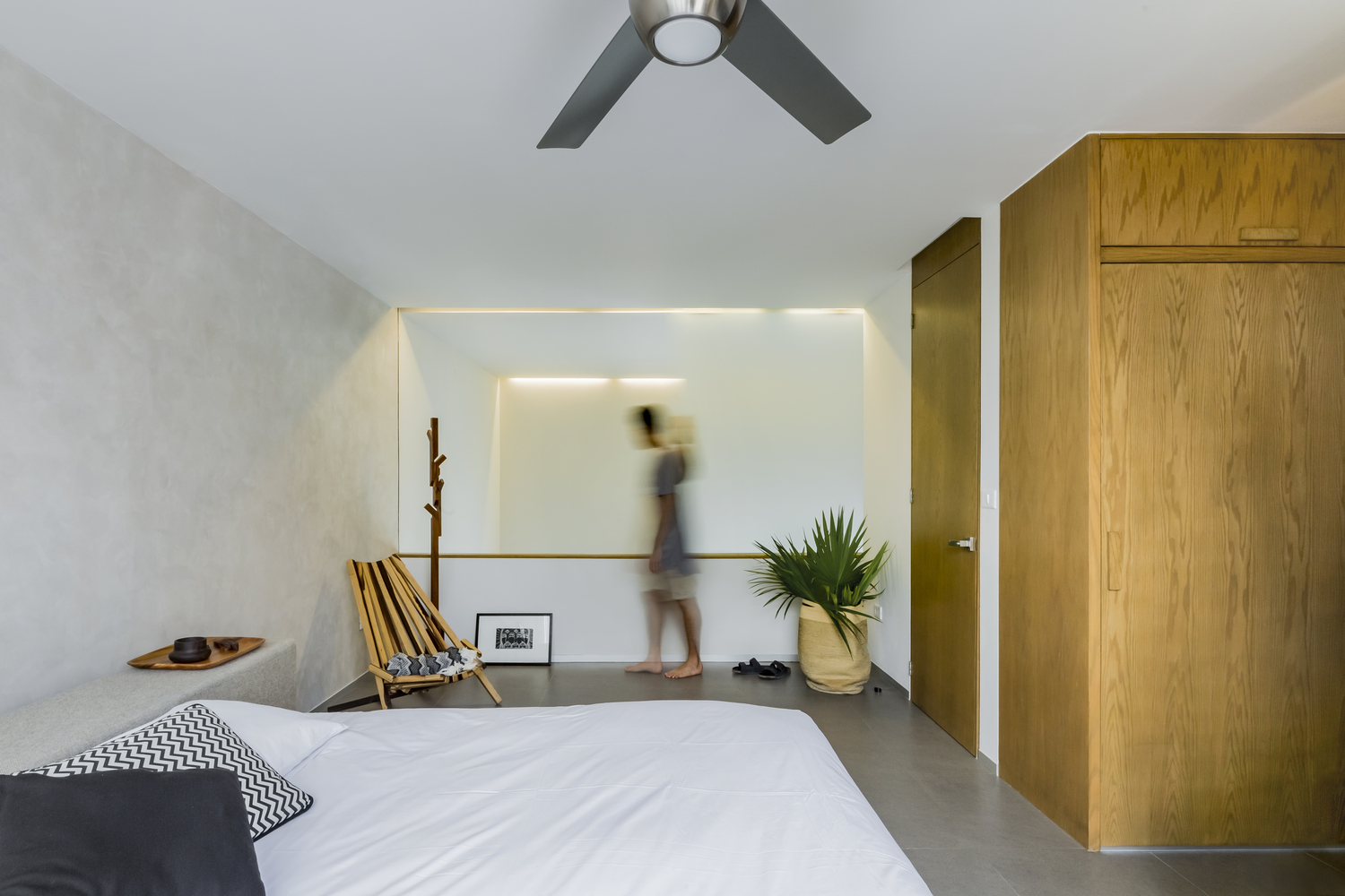 H&igrave;nh ảnh ph&ograve;ng ngủ c&oacute; thiết kế đơn giản với ga gối m&agrave;u trắng, tủ gỗ cao kịch trần, chậu c&acirc;y lớn đặt ở g&oacute;c ph&ograve;ng