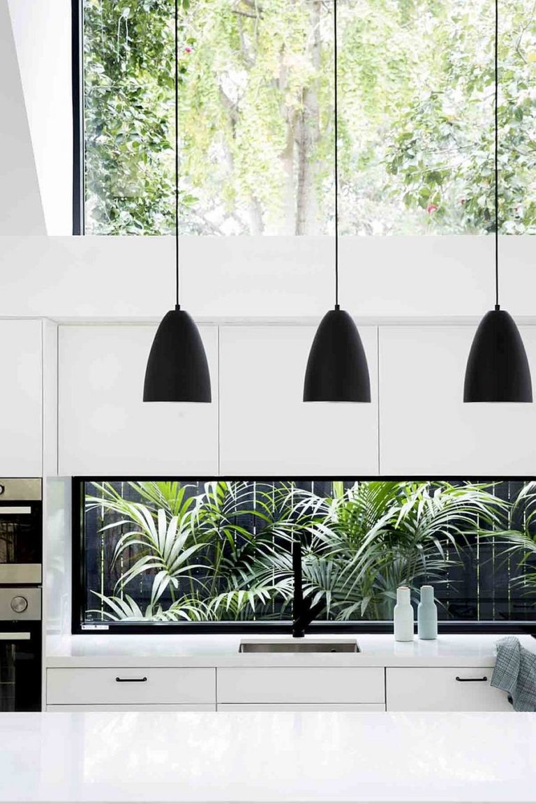 h&igrave;nh ảnh một g&oacute;c ph&ograve;ng bếp hiện đại với đ&egrave;n thả trần m&agrave;u đen, tủ bếp trắng, cửa sổ k&iacute;nh lớn