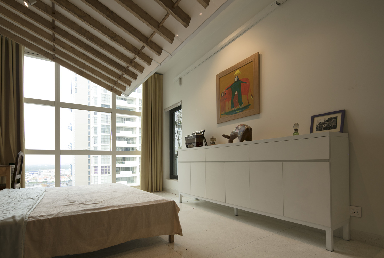 h&igrave;nh ảnh ph&ograve;ng ngủ hiện đại, tho&aacute;ng s&aacute;ng với tủ kệ lưu trữ m&agrave;u trắng, cửa sổ k&iacute;nh lớn, dầm gỗ lộ thi&ecirc;n