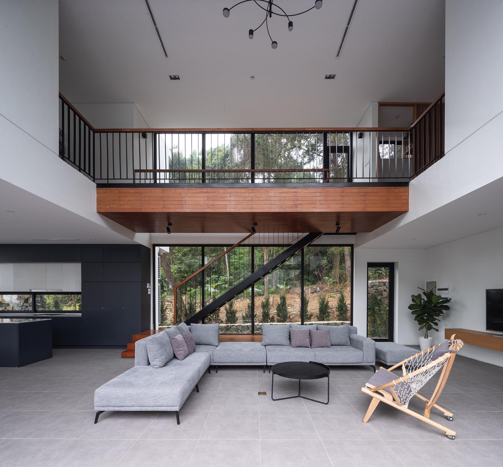 h&igrave;nh ảnh to&agrave;n cảnh ph&ograve;ng kh&aacute;ch biệt thự với sofa x&aacute;m trắng, ghế gỗ, b&agrave;n tr&agrave; tr&ograve;n m&agrave;u đen