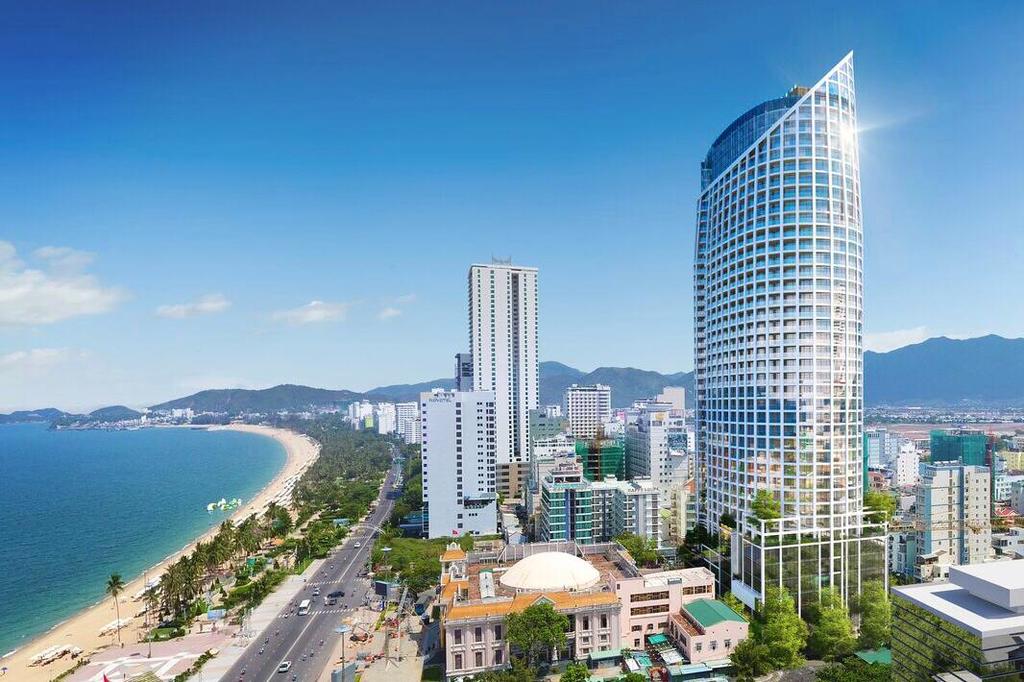 Thành phố nằm ven biển với bãi cát, một số tòa nhà cao tầng xen lẫn thấp tầng, nền trời xanh