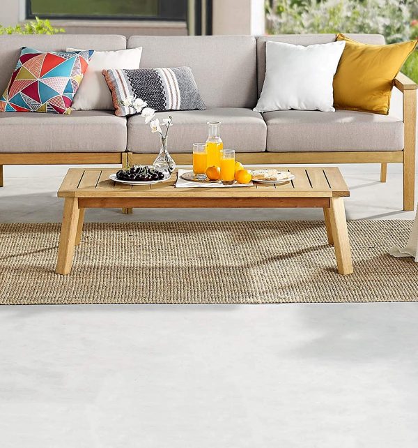 h&igrave;nh ảnh b&agrave;n c&agrave; ph&ecirc; ngo&agrave;i trời bằng gỗ bạch đ&agrave;n đặt tr&ecirc;n thảm c&oacute;i, cạnh đ&oacute; l&agrave; ghế sofa x&aacute;m khung gỗ, gối tựa m&agrave;u sắc