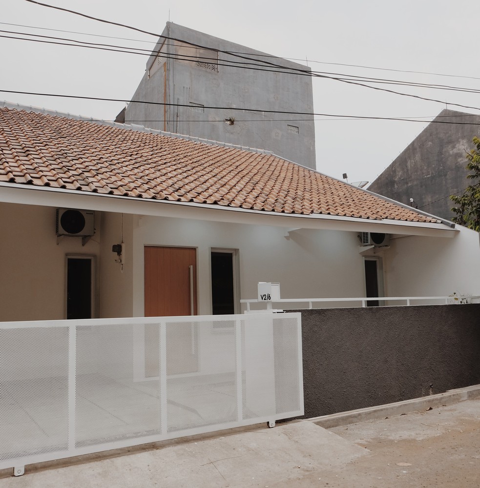 h&igrave;nh ảnh to&agrave;n cảnh mặt tiền ng&ocirc;i nh&agrave; 76m2 ở Indonesia sau khi cải tạo với m&aacute;i t&ocirc;n lượn s&oacute;ng, h&agrave;ng r&agrave;o kim loại sơn trắng