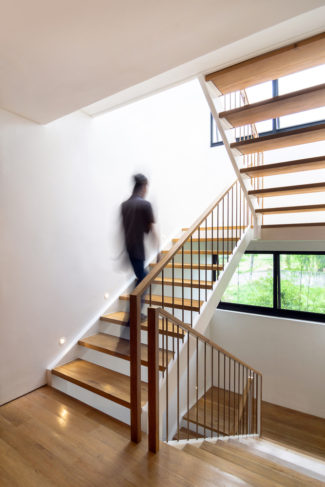 h&igrave;nh ảnh một người đ&agrave;n &ocirc;ng đang bước l&ecirc;n cầu thang bậc hở trong nh&agrave; 3 tầng