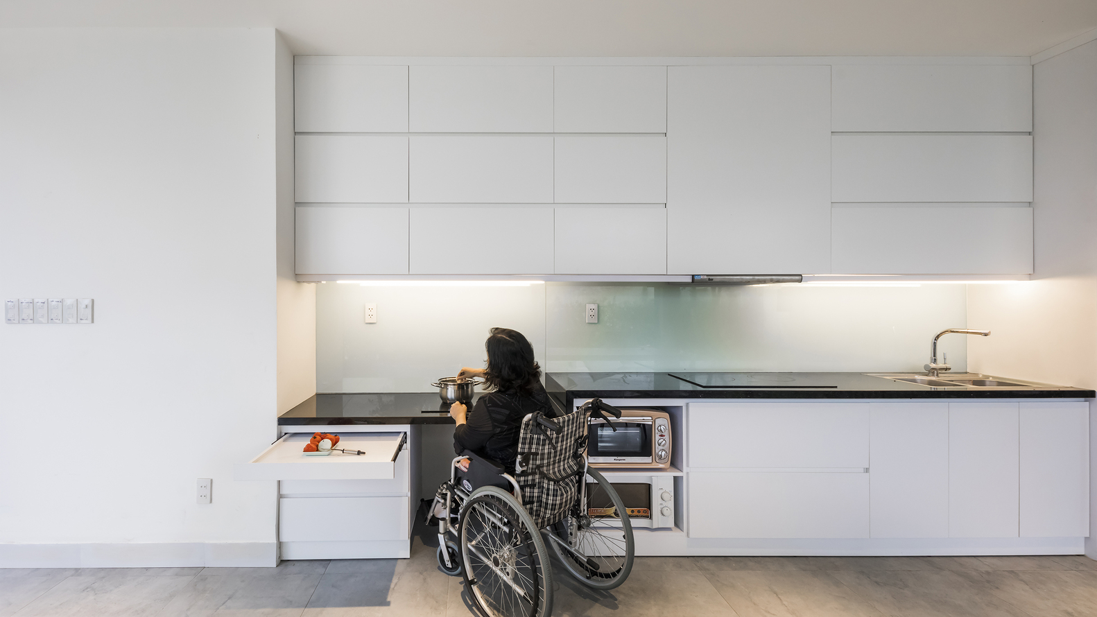 Người phụ nữ ngồi xe lăn đang nấu ăn trong ph&ograve;ng bếp gia đ&igrave;nh