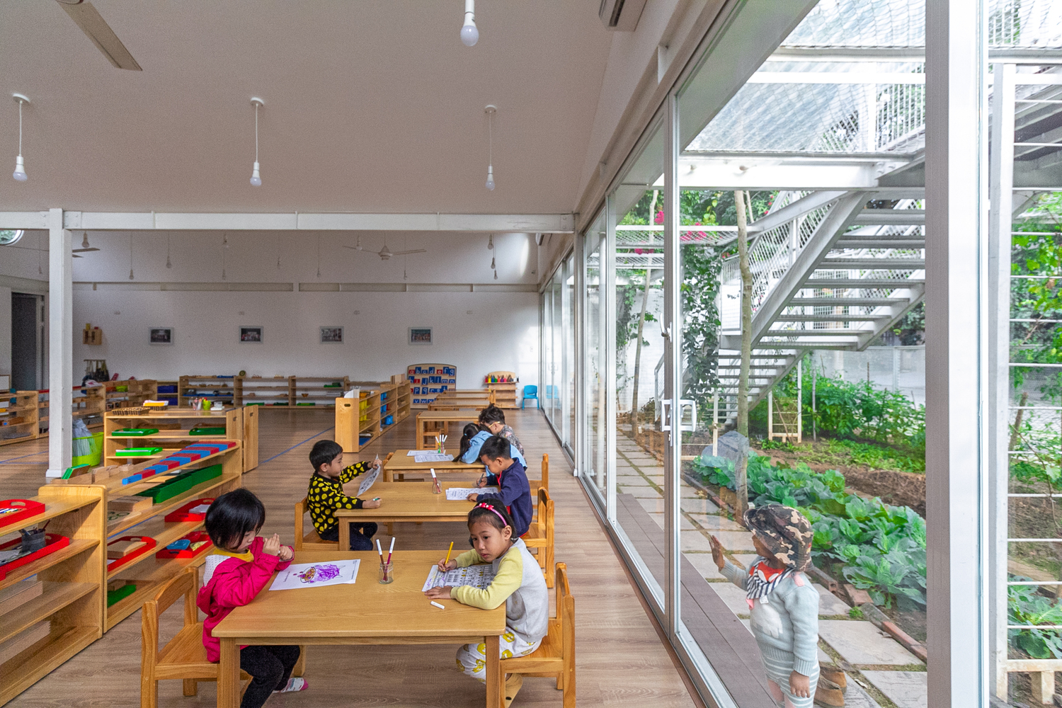 Trẻ em đang học tập, vui chơi trong lớp học giữa vườn c&acirc;y