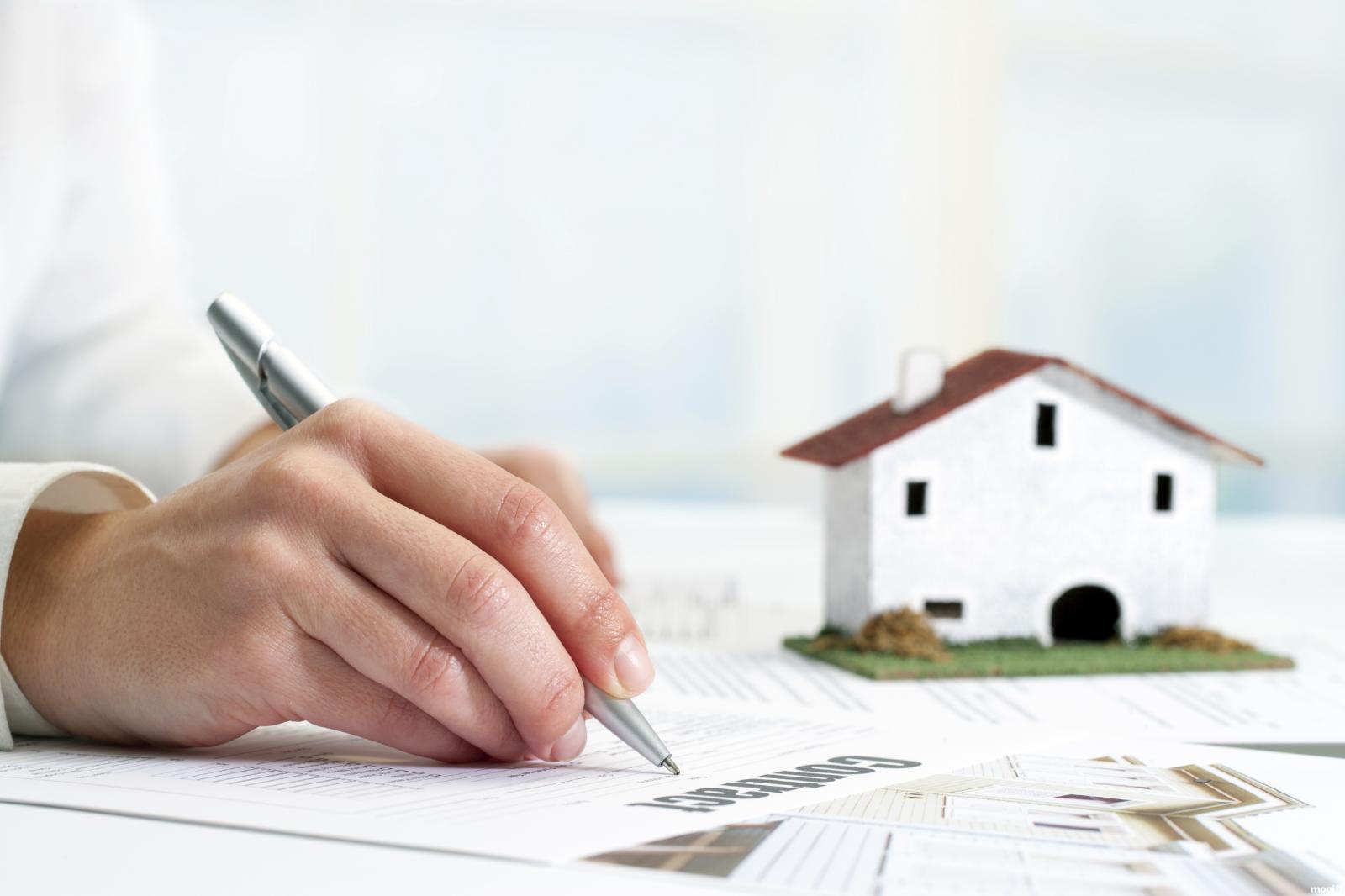 mua nhà qua giấy tờ tay một người đang viết hợp đồng mua bán nhà đất bằng giấy tay