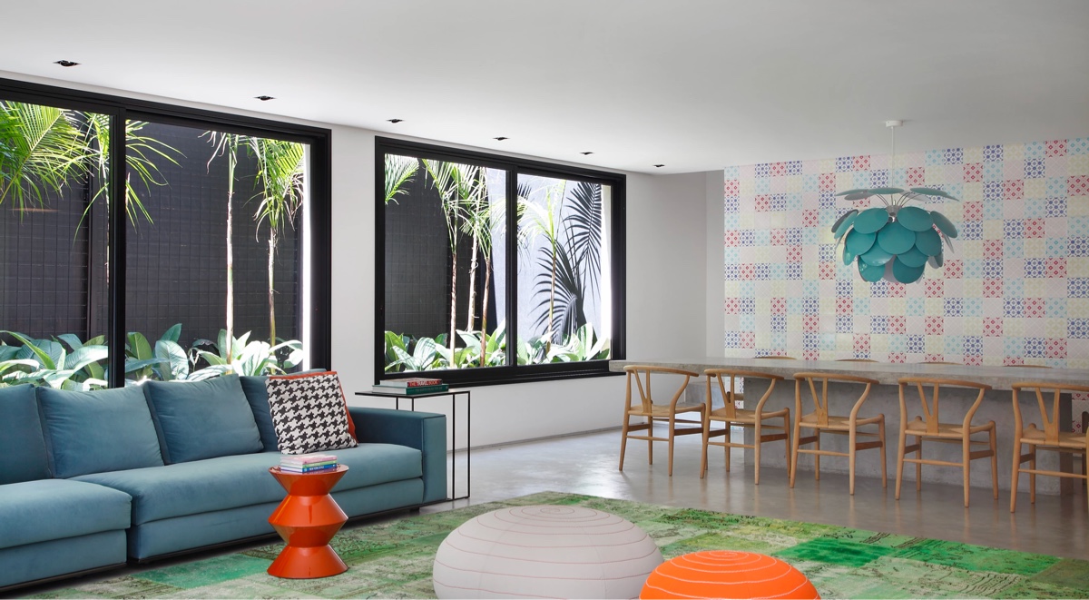 h&igrave;nh ảnh ph&ograve;ng kh&aacute;ch được thiết kế li&ecirc;n th&ocirc;ng ph&ograve;ng ăn với ghế sofa m&agrave;u xanh dương, b&agrave;n ghế băng bằng gỗ mộc mạc, cửa sổ k&iacute;nh lớn, b&ecirc;n ngo&agrave;i l&agrave; s&acirc;n vườn xanh m&aacute;t