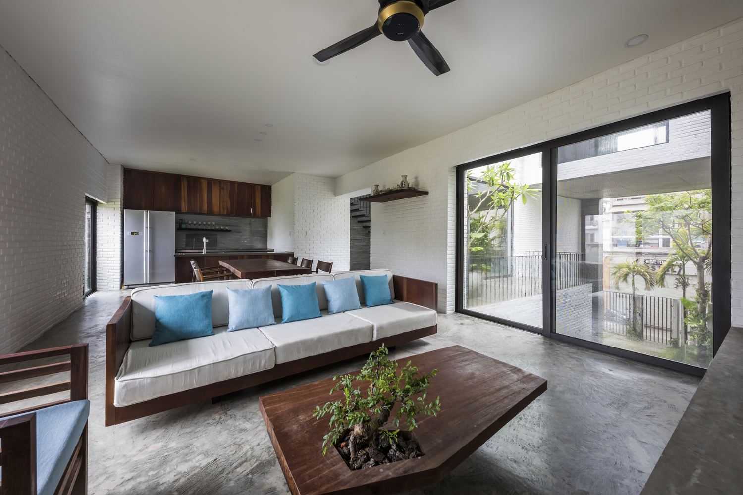 h&igrave;nh ảnh to&agrave;n cảnh ph&ograve;ng kh&aacute;ch nh&agrave; Thắng với sofa gỗ lọt đệm ngồi m&agrave;u trắng, b&agrave;n tr&agrave; gỗ t&iacute;ch hợp chậu c&acirc;y bonsai