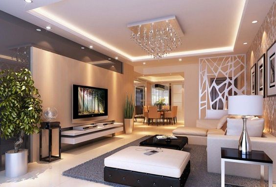 hình ảnh phòng khách biệt thự 2 tầng với kệ tivi gắn tường, sofa màu trắng sáng, chậu cảnh lớn ở góc, đèn chùm sang trọng