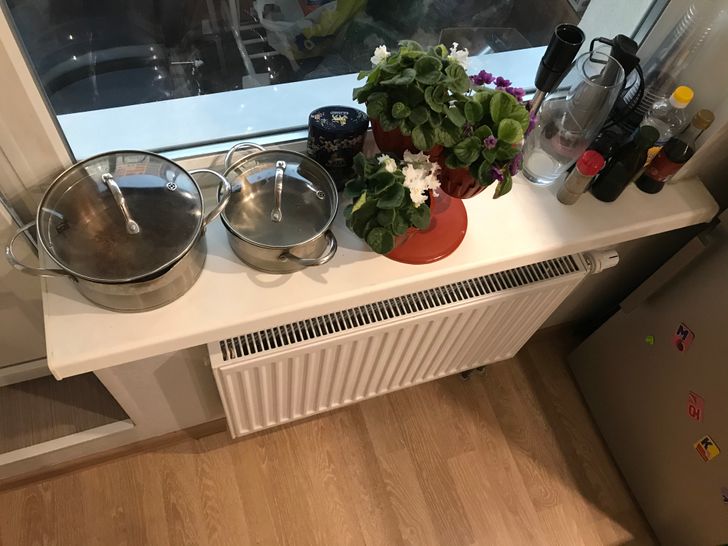 h&igrave;nh ảnh cận cảnh bệ cửa sổ chứa nhiều đồ đạc kh&aacute;c nhau như song nồi, chậu hoa, chai lọ, cốc ch&eacute;n, thiết bị nh&agrave; bếp