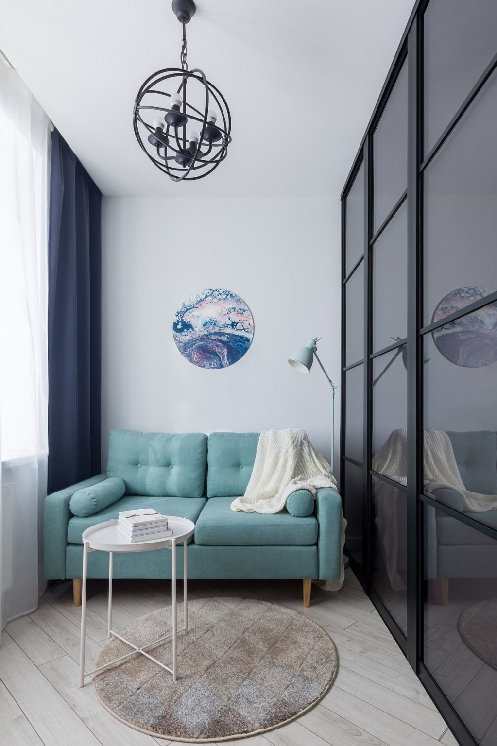 h&igrave;nh ảnh ph&ograve;ng kh&aacute;ch căn hộ studio nhỏ với ghế sofa m&agrave;u xanh da trời, b&agrave;n tr&ograve;n bằng kim loại đặt tr&ecirc;n thảm trải