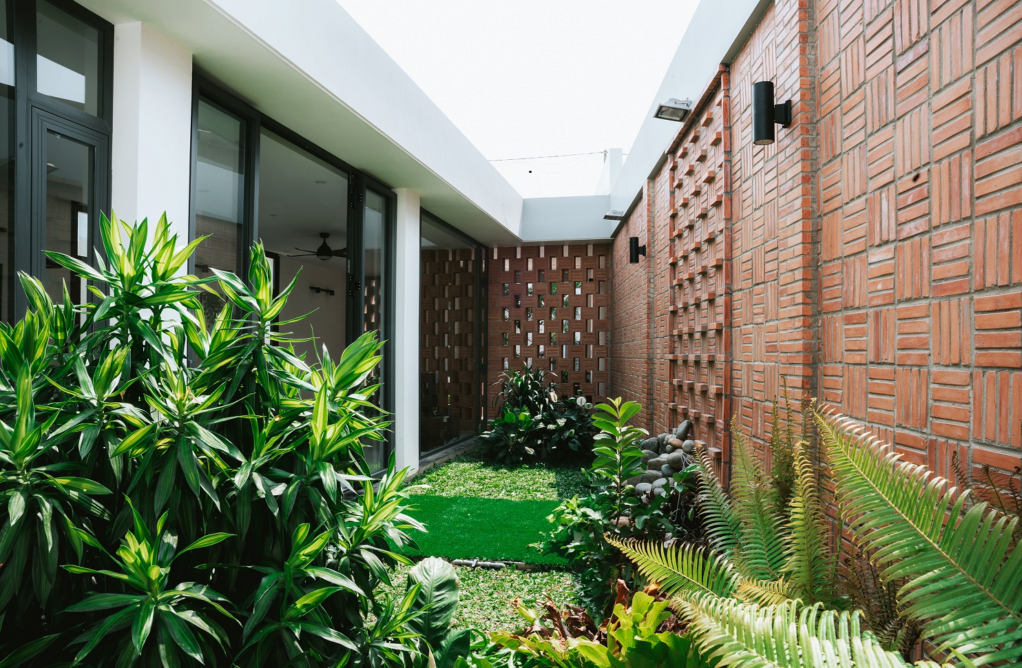 hình ảnh sân vườn xanh mát bên trong khuôn viên nhà cấp 4, nằm sau lớp tường gạch