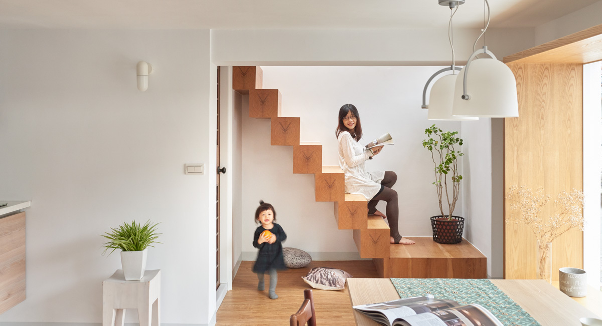 h&igrave;nh ảnh c&ocirc; g&aacute;i ngồi đọc s&aacute;ch tr&ecirc;n cầu thang gỗ nh&agrave; phố, b&ecirc;n dưới l&agrave; đứa trẻ đang vui đ&ugrave;a
