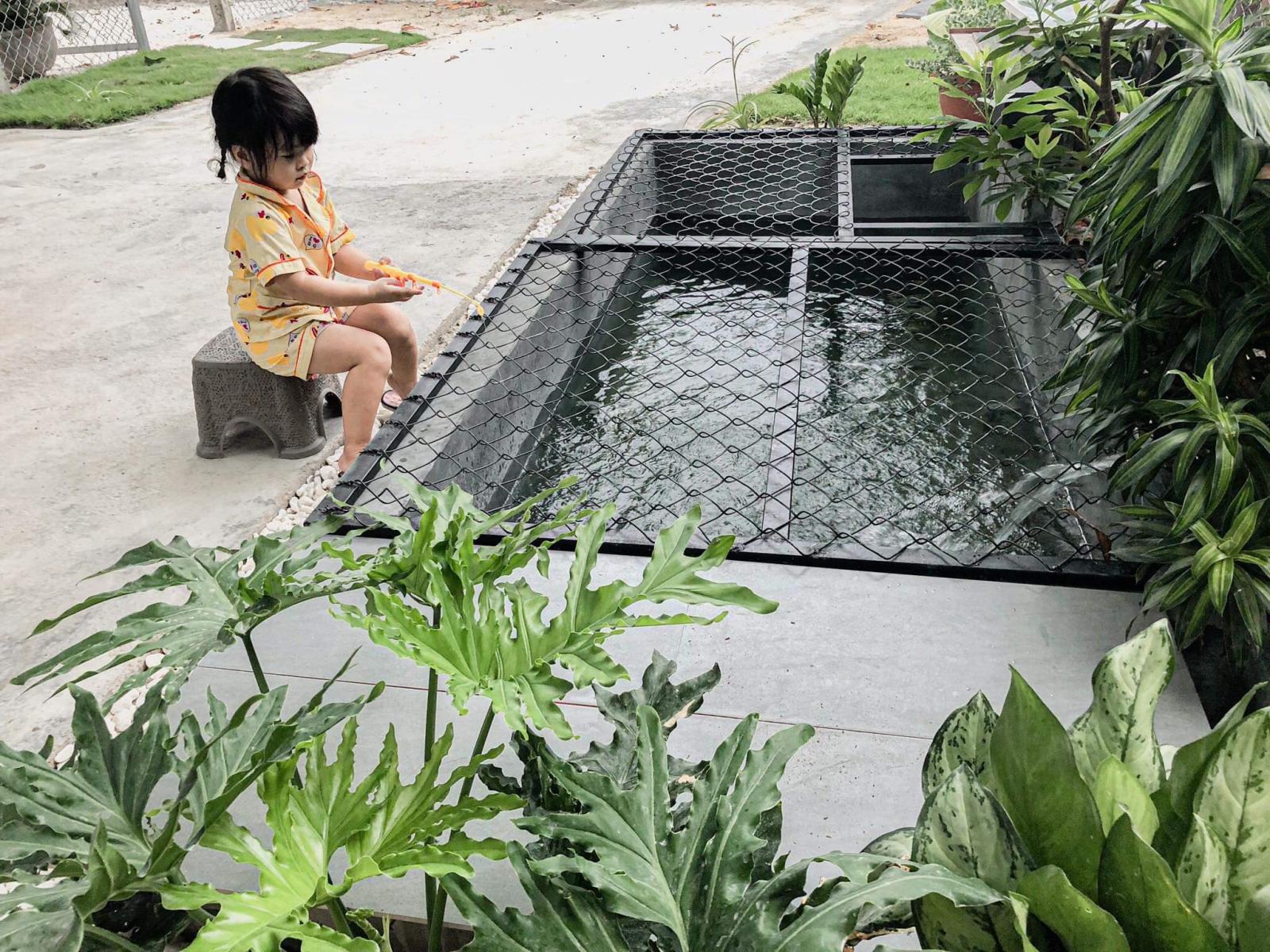 B&eacute; g&aacute;i ngồi b&ecirc;n bể c&aacute;