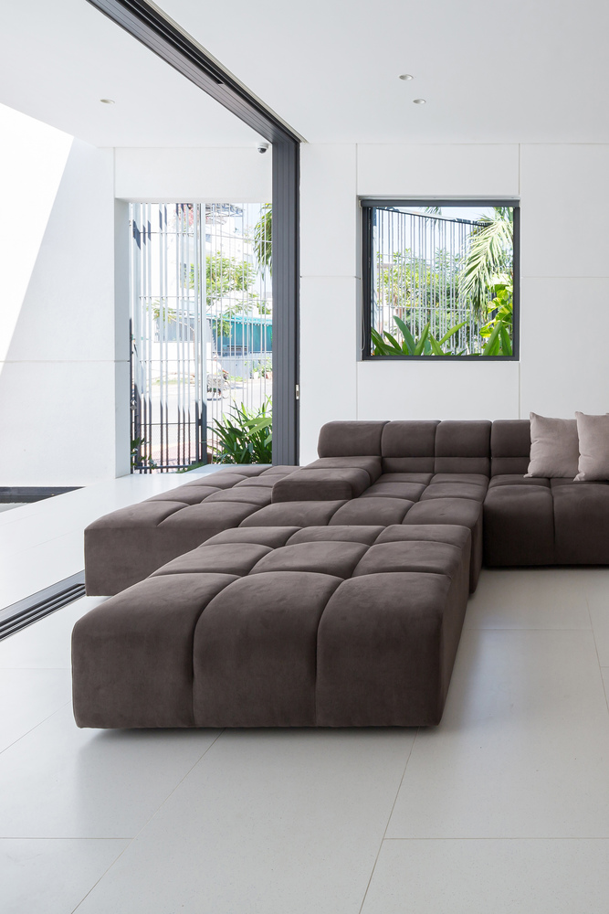 hình ảnh góc phòng khách sang trọng với sofa nâu êm ái, cửa cao rộng mở ra sân vườn bên ngoài