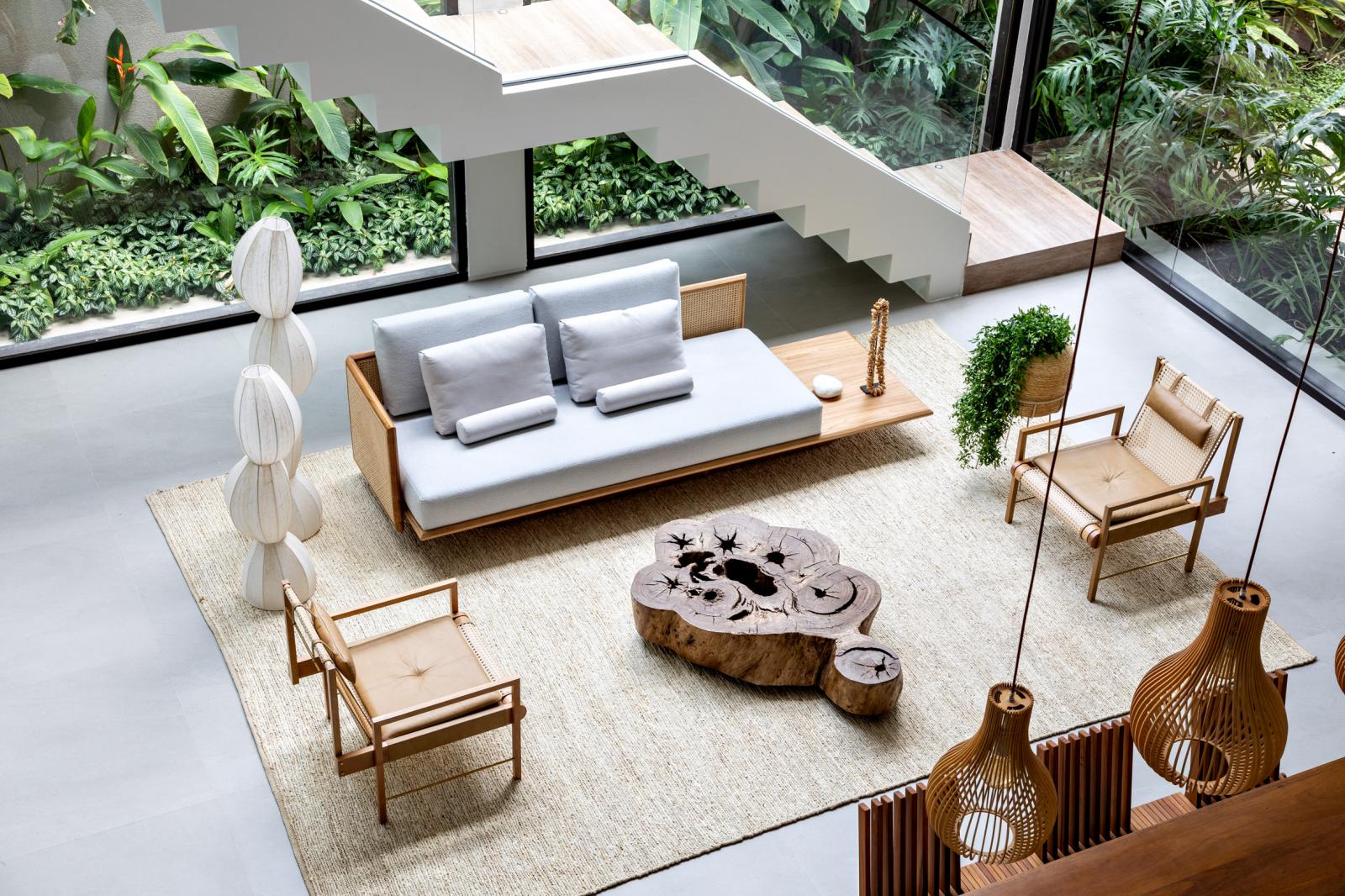 h&igrave;nh ảnh ph&ograve;ng kh&aacute;ch ở tầng trệt nh&igrave;n từ tr&ecirc;n cao với sofa gỗ bọc nệm m&agrave;u trung t&iacute;nh, b&agrave;n tr&agrave; gỗ nguy&ecirc;n khối
