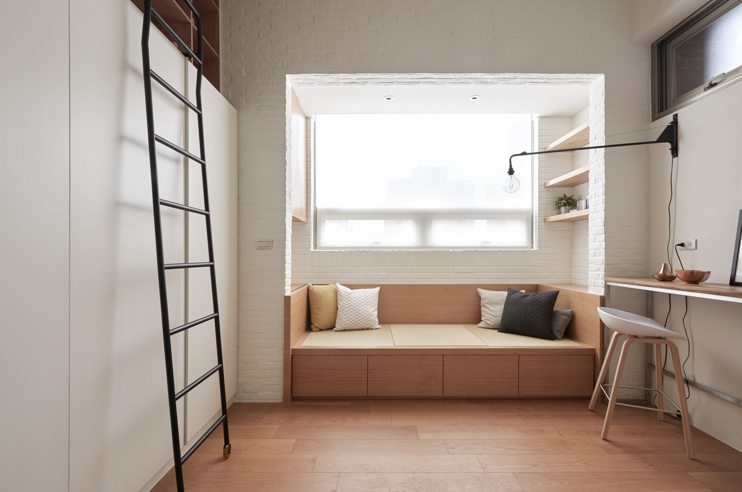 h&igrave;nh ảnh ghế ngồi b&ecirc;n cửa sổ căn hộ 22m2, cạnh đ&oacute; l&agrave; b&agrave;n l&agrave;m việc, thang m&agrave;u đen