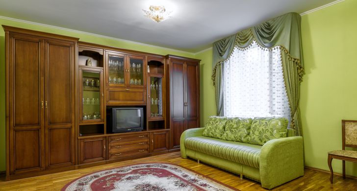 h&igrave;nh ảnh ph&ograve;ng kh&aacute;ch với sofa xanh l&aacute; c&acirc;y, tủ gỗ lưu trữ t&iacute;ch hợp kệ đặt tivi