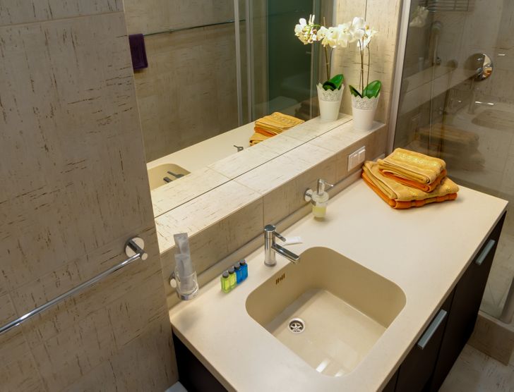 h&igrave;nh ảnh ph&ograve;ng tắm đơn giản, nổi bật với chiếc khăn tắm m&agrave;u v&agrave;ng đặt tr&ecirc;n bệ rửa