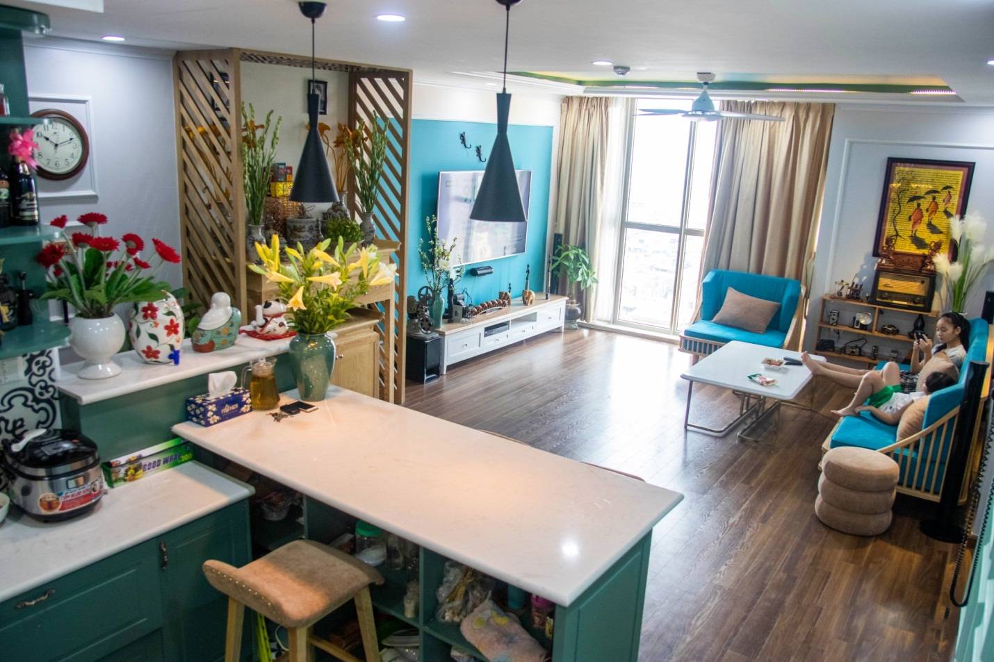 h&igrave;nh ảnh to&agrave;n cảnh ph&ograve;ng kh&aacute;ch căn hộ m&agrave;u xanh li&ecirc;n th&ocirc;ng với khu bếp