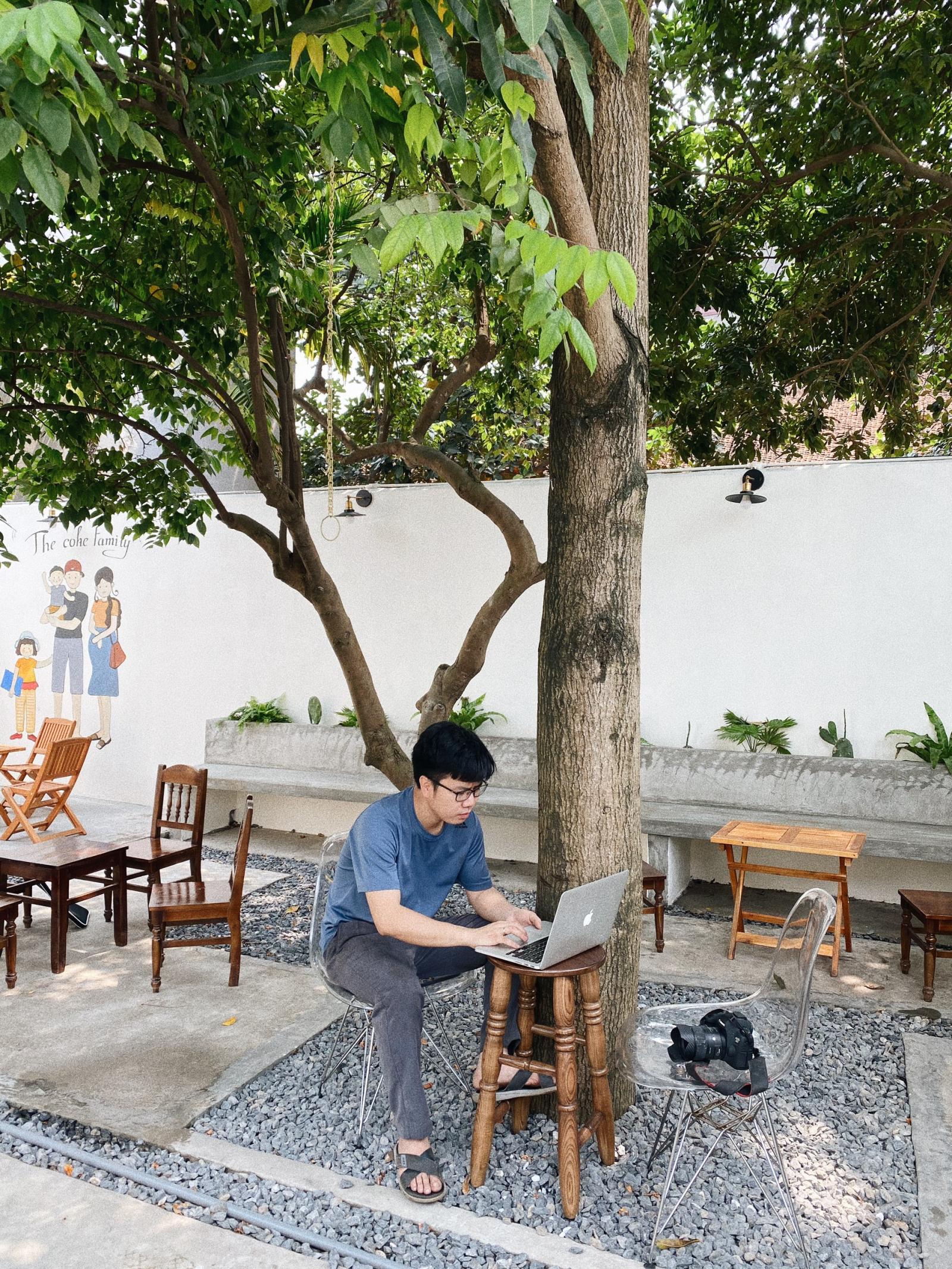 Gia chủ ngồi l&agrave;m việc ở b&agrave;n k&ecirc; ngo&agrave;i vườn c&acirc;y