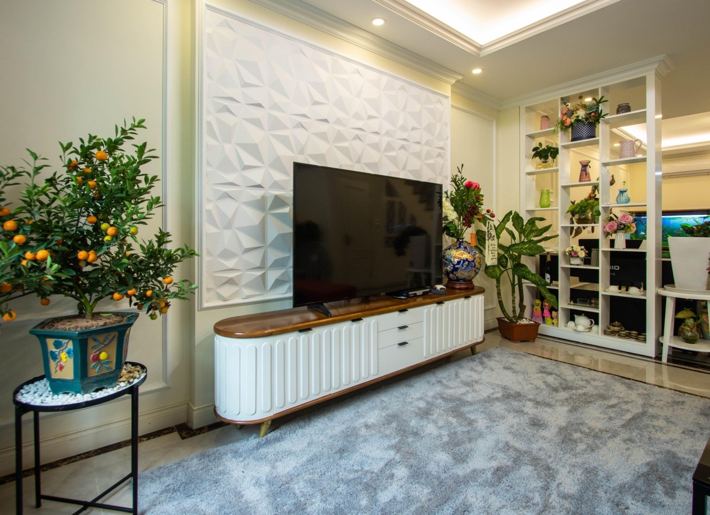 Bức tường ph&iacute;a sau kệ tivi được decor cực h&uacute;t mắt với t&ocirc;ng m&agrave;u trắng thuần khiết v&agrave; những đường n&eacute;t h&igrave;nh học đi&ecirc;u khắc ấn tượng.