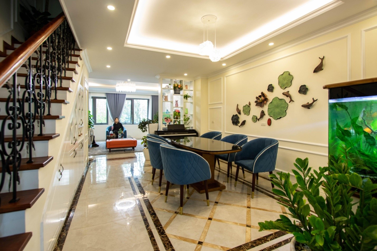 Căn ph&ograve;ng to&aacute;t l&ecirc;n vẻ sang trọng, lịch l&atilde;m với bộ ghế ăn bọc nệm m&agrave;u xanh dương, họa tiết &aacute;nh kim tr&ecirc;n s&agrave;n nh&agrave; v&agrave; đ&egrave;n thả mặt d&acirc;y chuyền mềm mại.