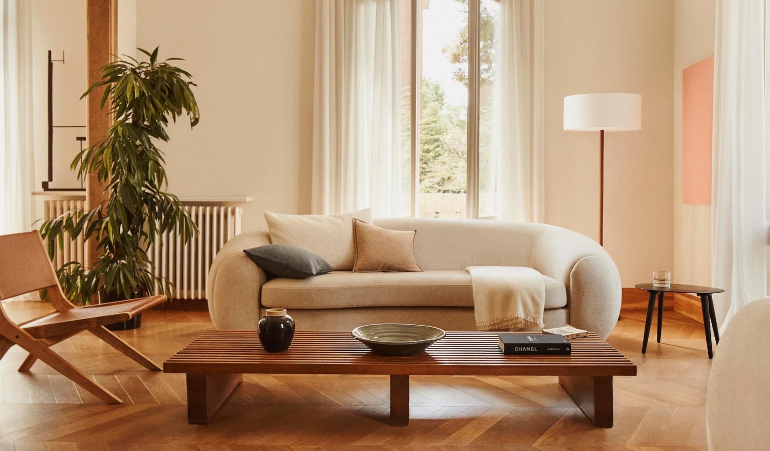 hình ảnh một phòng khách với sofa màu trắng êm ái, bàn trà gỗ, cây xanh trang trí, cửa sổ kính ngập tràn ánh sáng