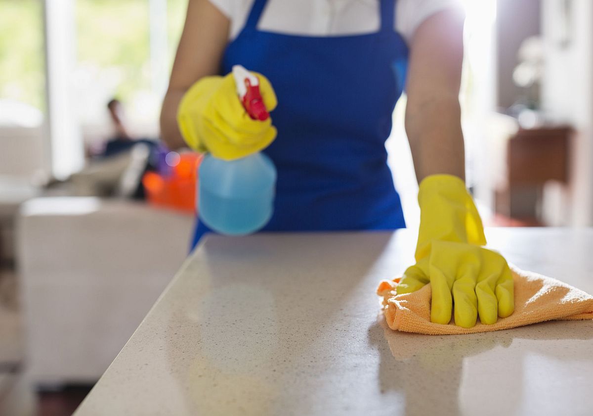 h&igrave;nh ảnh một người phụ nữ đang d&ugrave;ng b&igrave;nh xịt vệ sinh b&agrave;n bếp