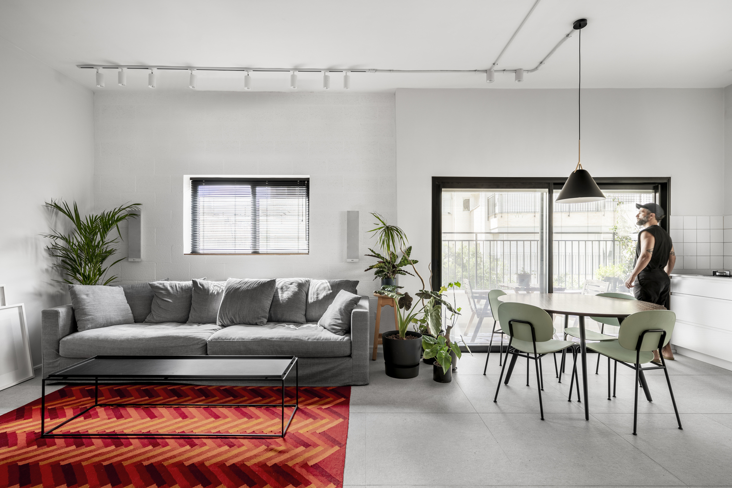 h&igrave;nh ảnh ph&ograve;ng kh&aacute;ch li&ecirc;n th&ocirc;ng ph&ograve;ng ăn trong căn hộ 75m2 với sofa x&aacute;m, thảm trải m&agrave;u đỏ