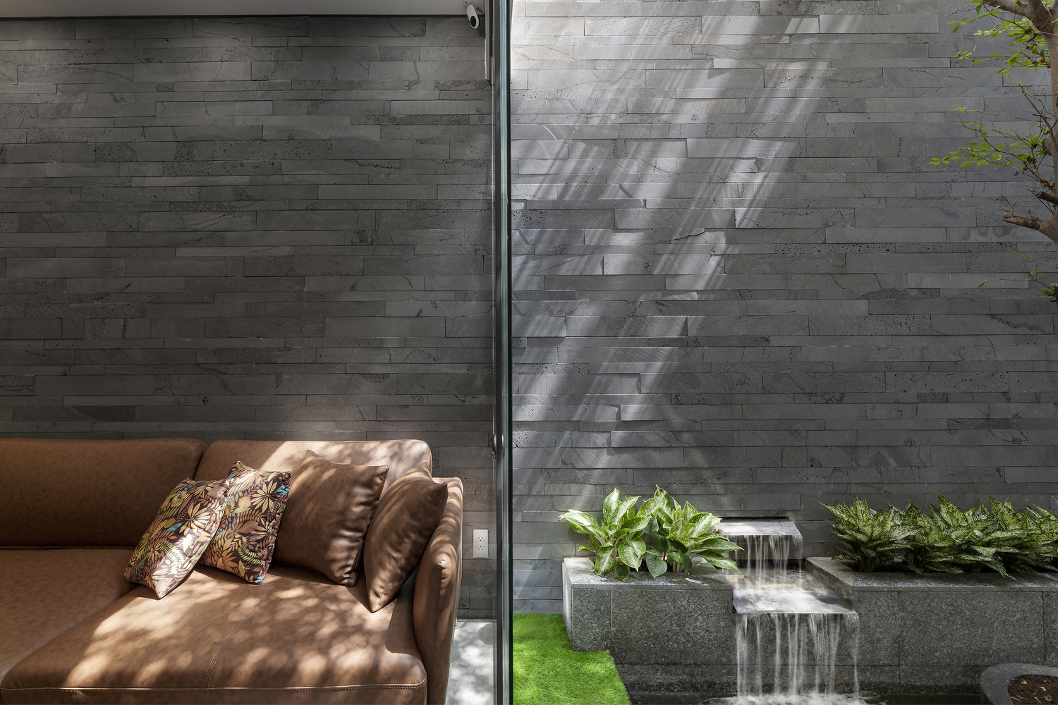 Một g&oacute;c sofa thư gi&atilde;n b&ecirc;n cạnh hồ c&aacute; Koi, hướng nh&igrave;n ra những vệt nắng k&eacute;o d&agrave;i từ s&acirc;n thượng đến bức tường đ&aacute; ong.